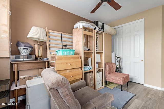 interior space featuring a ceiling fan, a closet, baseboards, and wood finished floors