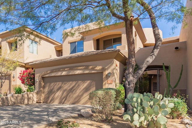 adobe home with concrete driveway and an attached garage