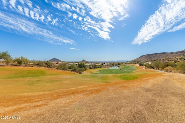 surrounding community featuring view of golf course, a mountain view, and a lawn