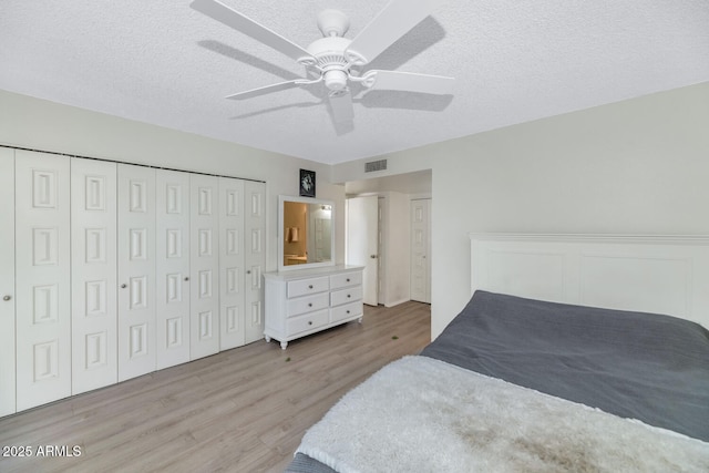 bedroom with ceiling fan, light hardwood / wood-style floors, and a textured ceiling