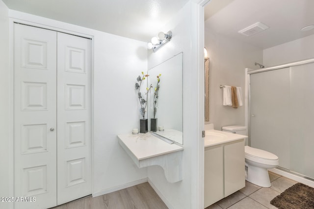 bathroom featuring a shower with door, vanity, tile patterned flooring, and toilet