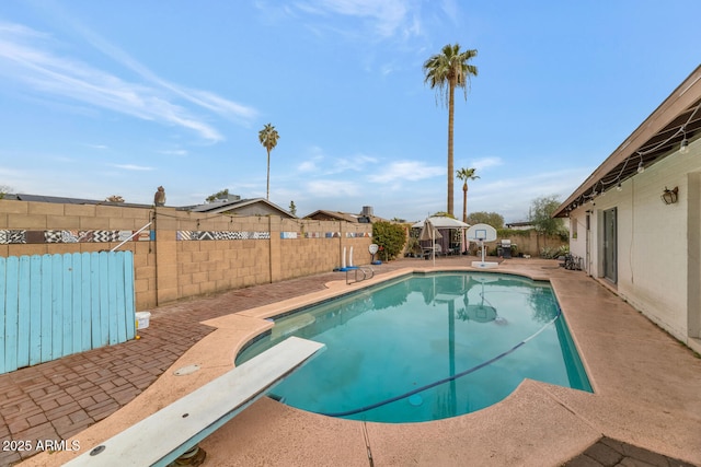 view of swimming pool featuring a diving board and a patio area