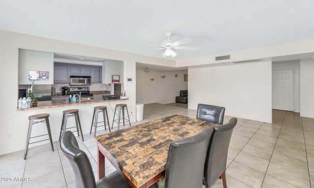 dining space featuring sink, ceiling fan, and light tile patterned flooring