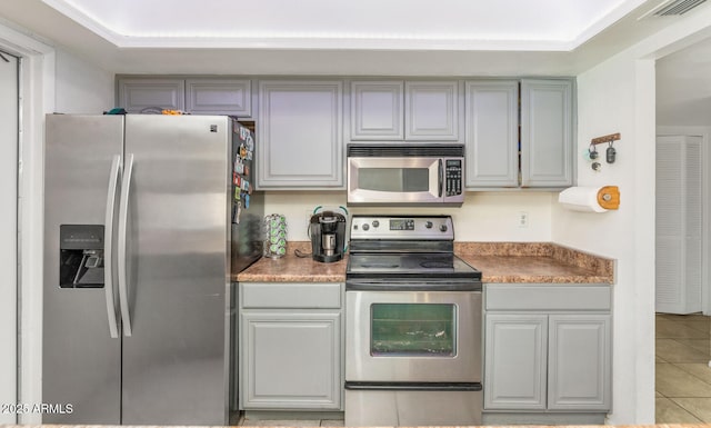 kitchen featuring gray cabinetry, light tile patterned floors, and stainless steel appliances