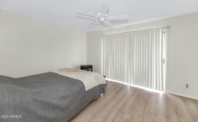 bedroom featuring ceiling fan, light hardwood / wood-style flooring, and a textured ceiling