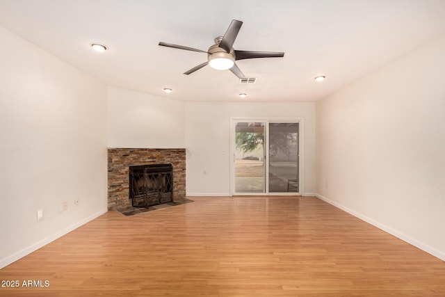 unfurnished living room featuring light hardwood / wood-style flooring, a stone fireplace, and ceiling fan