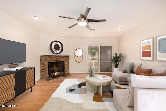 living room with ceiling fan, a fireplace, and light hardwood / wood-style flooring