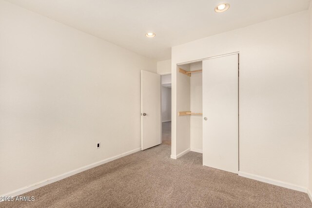 unfurnished bedroom featuring light carpet and a closet