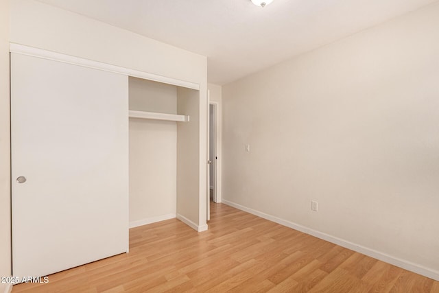 unfurnished bedroom featuring light wood-type flooring and a closet