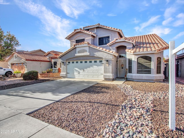 mediterranean / spanish-style house with a garage, driveway, a tile roof, and stucco siding