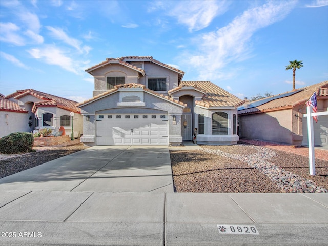 mediterranean / spanish house featuring a garage, concrete driveway, a tile roof, and stucco siding