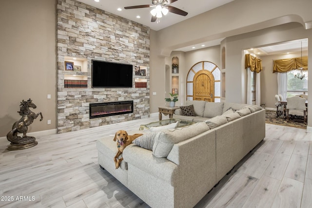 6861 W Calle Lejos, Peoria, AZ 85383 - living room featuring wood finished floors, a ceiling fan, arched walkways, recessed lighting, and a stone fireplace