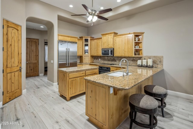6861 W Calle Lejos, Peoria, AZ 85383 - kitchen with black appliances, ceiling fan, a peninsula, decorative backsplash, and light stone countertops
