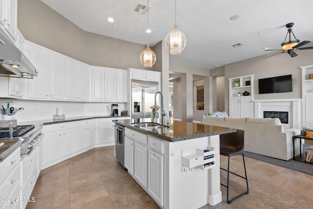 kitchen featuring white cabinets, an island with sink, decorative light fixtures, appliances with stainless steel finishes, and a breakfast bar area