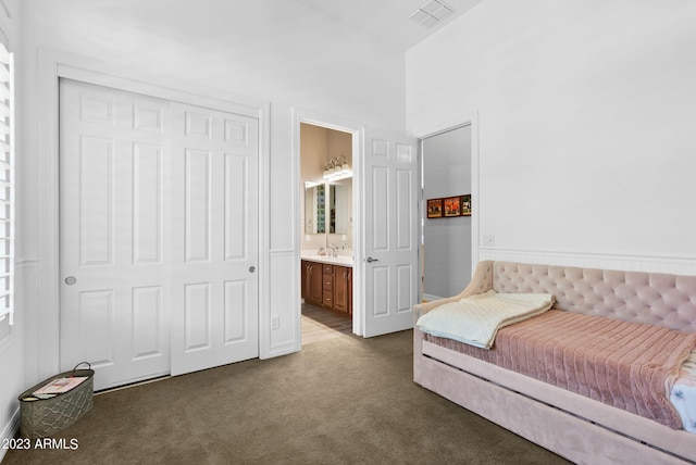 carpeted bedroom with sink, a closet, and ensuite bathroom