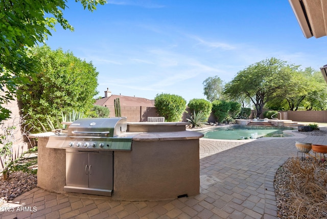 view of patio with a fenced in pool, an outdoor kitchen, and area for grilling