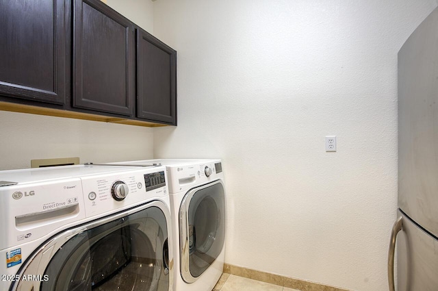 laundry area with washing machine and dryer, light tile patterned flooring, cabinet space, and baseboards