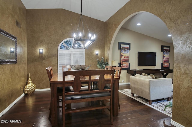 dining room with baseboards, lofted ceiling, hardwood / wood-style floors, and arched walkways