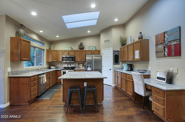 kitchen with dark wood-style flooring, visible vents, a sink, a kitchen island, and appliances with stainless steel finishes