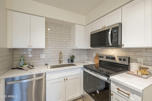 kitchen featuring tasteful backsplash, white cabinets, stainless steel appliances, and a sink