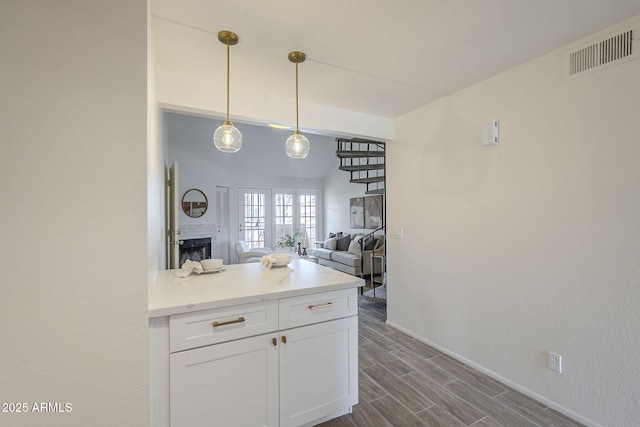 kitchen featuring visible vents, wood finish floors, decorative light fixtures, light countertops, and white cabinets