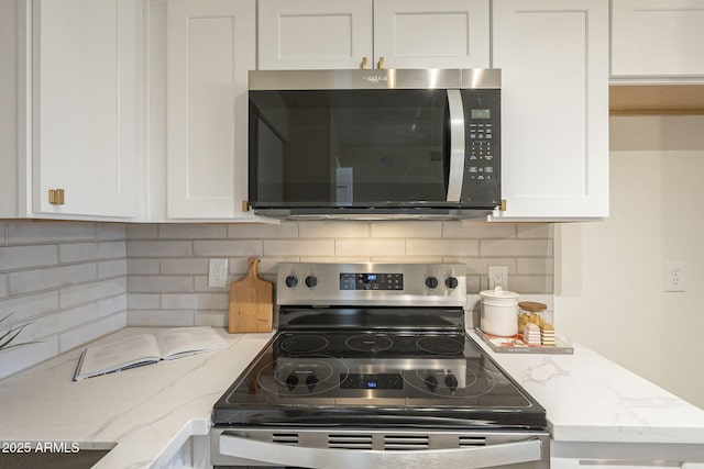 kitchen featuring light stone counters, stainless steel appliances, backsplash, and white cabinets