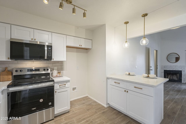 kitchen featuring stainless steel appliances, tasteful backsplash, white cabinets, and wood tiled floor