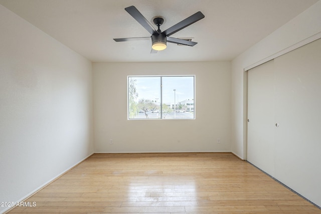 unfurnished bedroom featuring light wood-style flooring, a ceiling fan, and a closet