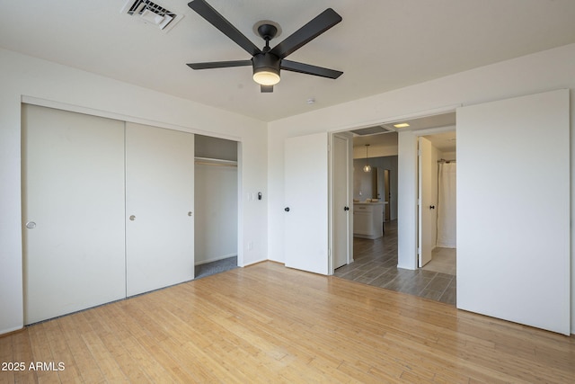 unfurnished bedroom with ceiling fan, a closet, visible vents, and wood finished floors