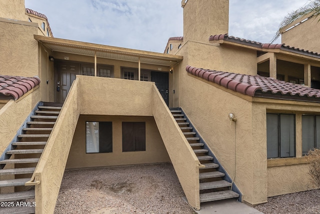 exterior space featuring stairway, stucco siding, and a tile roof