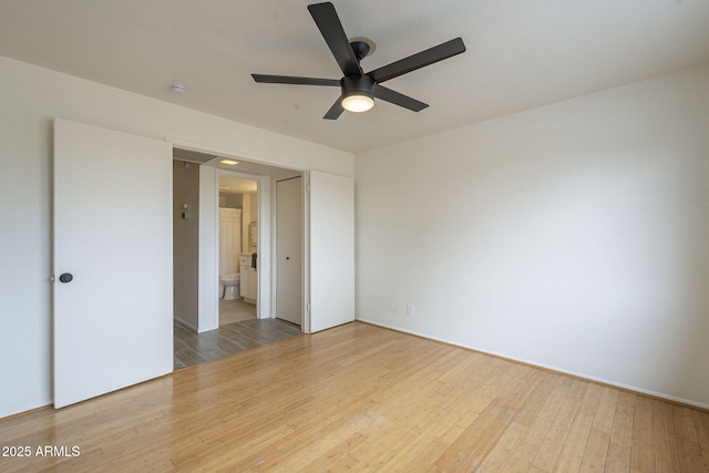 unfurnished bedroom featuring ensuite bath, ceiling fan, and wood finished floors