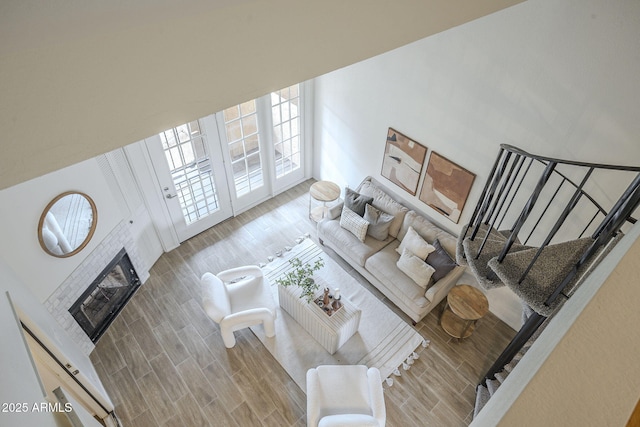 living area featuring a tiled fireplace, stairway, and wood finished floors