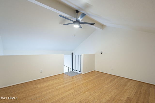 additional living space with baseboards, vaulted ceiling with beams, light wood-type flooring, and a ceiling fan