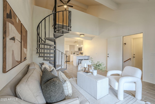 living room featuring high vaulted ceiling, ceiling fan, stairs, beamed ceiling, and light wood-type flooring