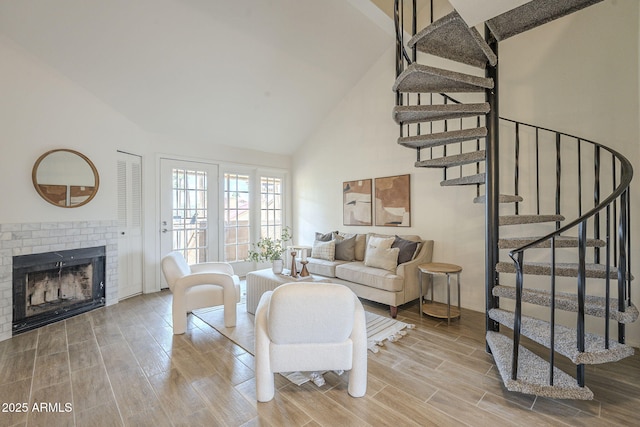 living room with stairway, a fireplace, high vaulted ceiling, and wood tiled floor