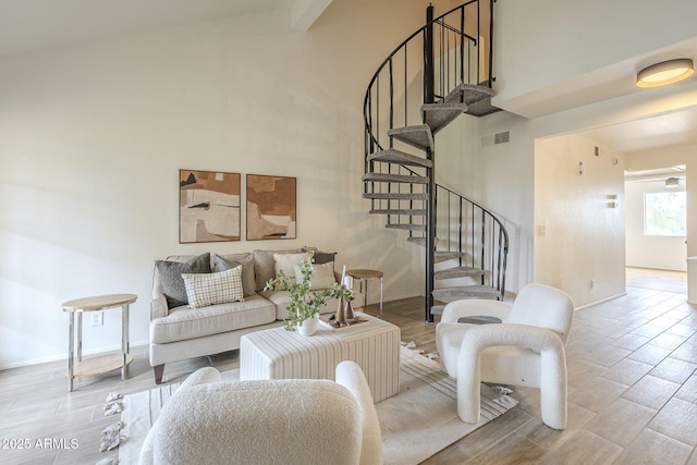 living room with wood finish floors, visible vents, baseboards, a towering ceiling, and stairs