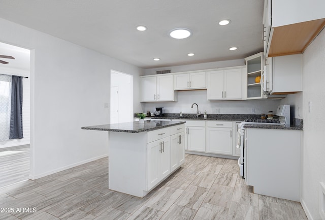 kitchen featuring a sink, open shelves, dark stone counters, white range with electric stovetop, and a kitchen island