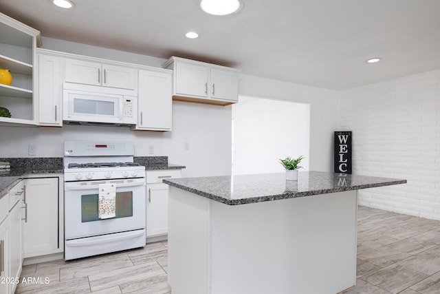kitchen featuring white cabinetry, white appliances, open shelves, and dark stone counters