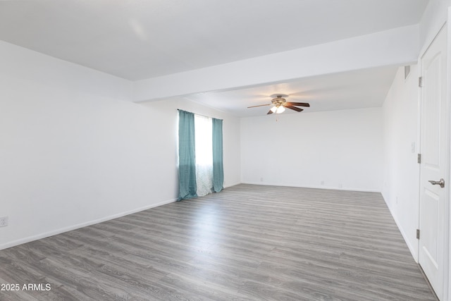spare room featuring a ceiling fan, baseboards, and wood finished floors