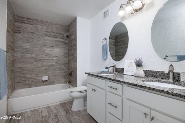 bathroom with double vanity, toilet, visible vents, and a sink