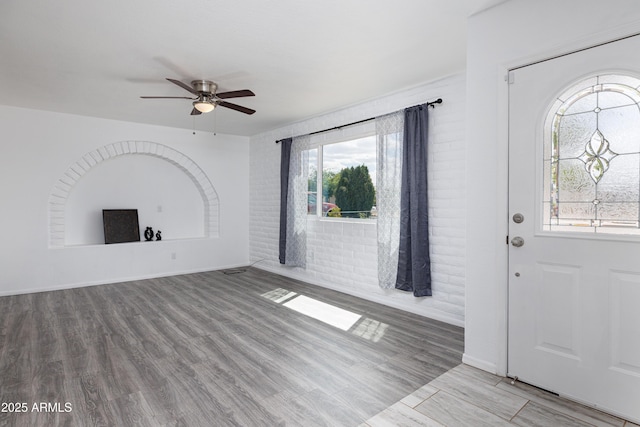 interior space featuring a wealth of natural light, baseboards, a ceiling fan, and wood finished floors
