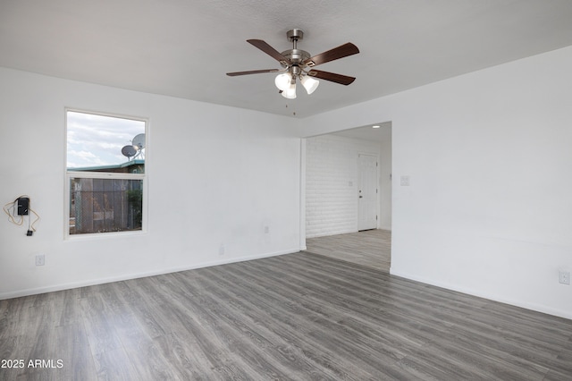 empty room featuring baseboards, a ceiling fan, and wood finished floors