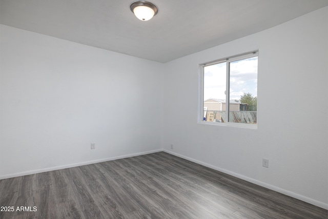 unfurnished room with baseboards and dark wood-style floors