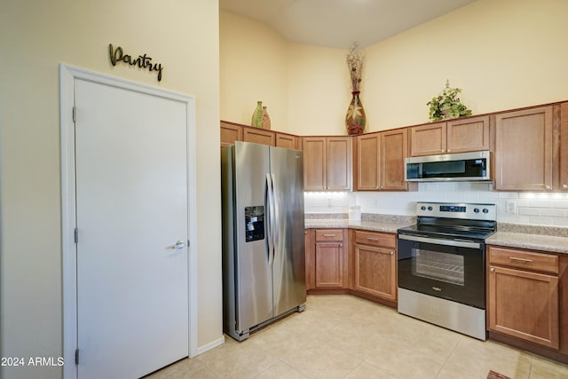 kitchen featuring backsplash, light tile patterned floors, stainless steel appliances, and vaulted ceiling