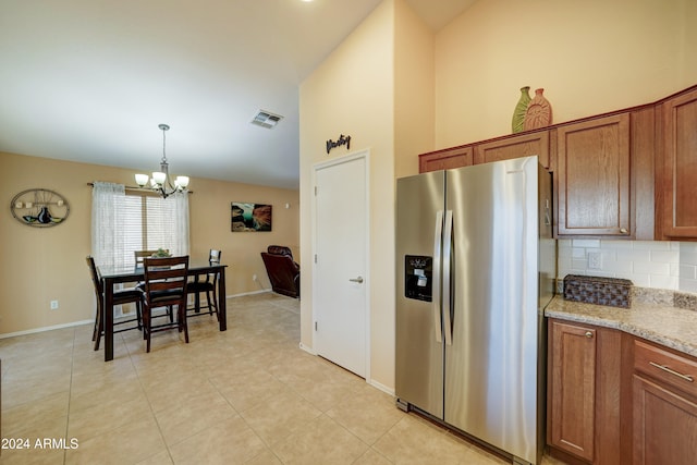 kitchen featuring light stone countertops, tasteful backsplash, decorative light fixtures, a chandelier, and stainless steel fridge with ice dispenser