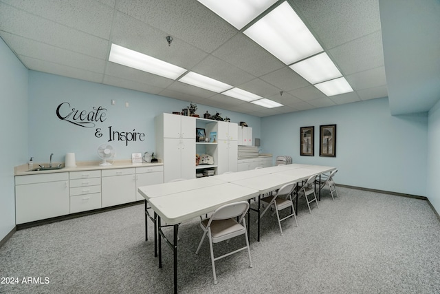 carpeted dining area with a paneled ceiling