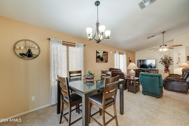 tiled dining room featuring ceiling fan with notable chandelier, a healthy amount of sunlight, and vaulted ceiling