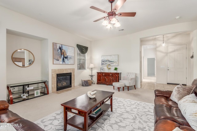 living room featuring carpet floors, ceiling fan, a tile fireplace, and visible vents