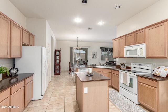 kitchen featuring visible vents, a center island, a sink, white appliances, and a peninsula