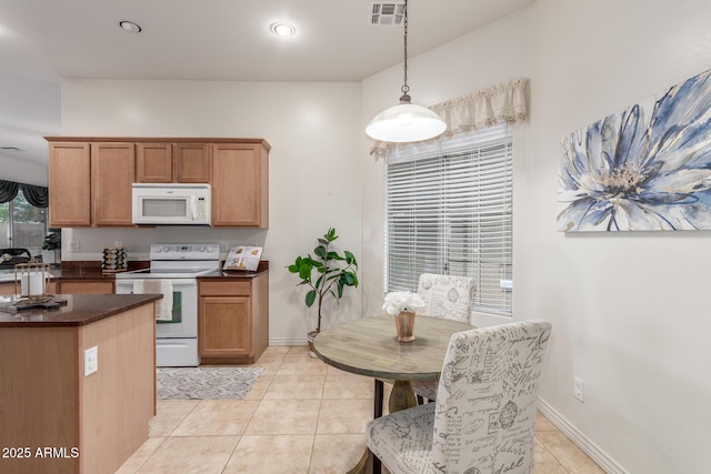 kitchen with baseboards, white appliances, light tile patterned flooring, dark countertops, and visible vents